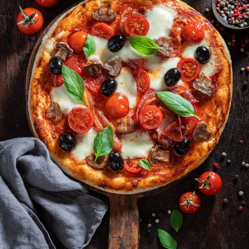 Delicious pizza Capricciosa with prosciutto, cheese and mushrooms