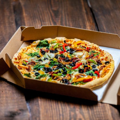 mediterranean Pizza with olives and cheese in cardboard on wooden table